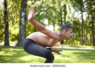 Sporty Handsome Indian Young Man Working Out In Park, Preparing For Half Lotus Tip Toe Pose, Ardha Baddha Padma Padangusthasana, Padangustha Padma Utkatasana, Side View