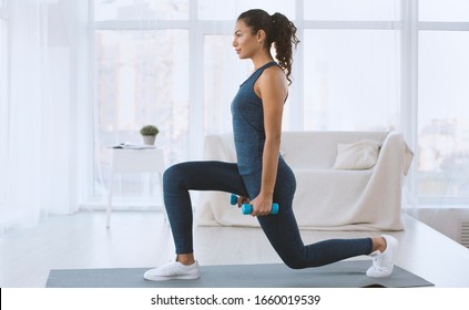 Sporty Hispanic girl doing lunges with dumbbells at home, empty space - Powered by Shutterstock