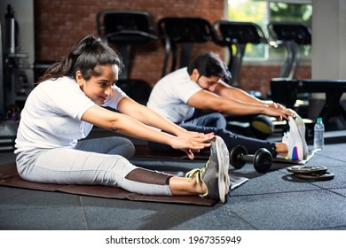 Sporty Indian Asian Young Couple Stretching In Gym Post Exercise For Cooling Down, Improving Flexibility