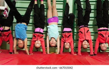 Sporty Kids Making Handstand Position In Gym