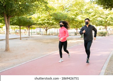 Sporty Latin Couple With Face Masks Are Training In The Running Track Of The Park During The Covid 19 Pandemic 