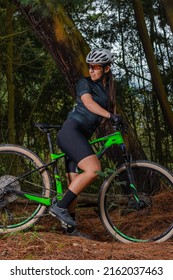 Sporty Latin Woman Riding Her Bike With One Foot Resting Looking Back