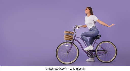 Sporty Lifestyle. Young Casual Woman Riding Bike At Studio Isolated Over Pastel Purple Wall, Banner, Copy Space