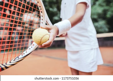 Sporty little girl preparing to serve tennis ball. Close up view of beautiful yong girl holding tennis ball and racket. Child tennis player preparing to serve.