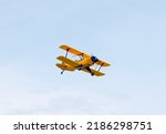 A sporty looking yellow  plane in flight
