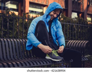 Sporty Man In A Blue Sports Jacket Ties His Sneakers.