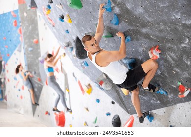 Sporty man in doing a difficult wall climb in climbing gym without special climbing equipment - Powered by Shutterstock