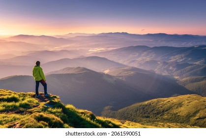 Sporty man on the mountain peak looking on mountain valley with sunbeams at colorful sunset in autumn in Europe. Landscape with traveler, foggy hills, forest in fall, amazing sky and sunlight in fall - Shutterstock ID 2061590051