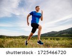 sporty man runner running on mountain plateau in summer