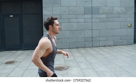 Sporty Man Running Outdoor. Male Runner Jogging On City Street In Slow Motion. Fit Guy Training Run Exercise On Urban Street. Fitness Man Running At City Street