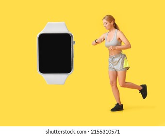 Sporty mature female runner checking her pulse and big smartwatch with blank screen on yellow background 