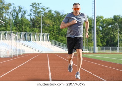 Sporty Mature Man Jogging At Stadium