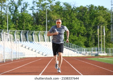 Sporty Mature Man Jogging At Stadium