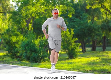 Sporty Mature Man In Sunglasses Running In Park