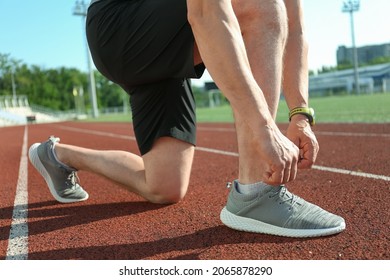 Sporty Mature Man Tying Shoe Laces At Stadium, Closeup