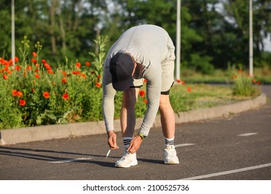 Sporty Mature Man Tying Shoe Laces On Road