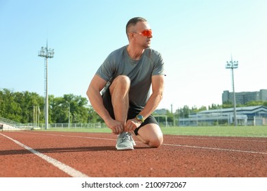 Sporty Mature Man Tying Shoe Laces At Stadium