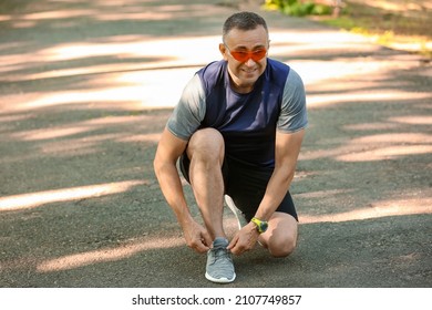 Sporty Mature Man Tying Shoe Laces In Park