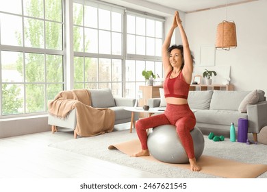 Sporty mature woman doing yoga on fitball at home - Powered by Shutterstock