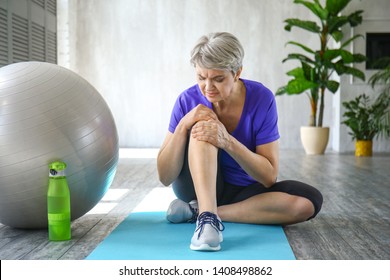 Sporty Mature Woman With Injured Knee After Training At Home