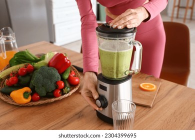 Sporty mature woman making healthy smoothie with blender in kitchen, closeup - Powered by Shutterstock