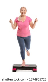 Sporty Mature Woman Training With Stepper On White Background