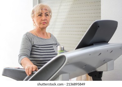 Sporty Mature Woman Using Indoors Treadmill At Home