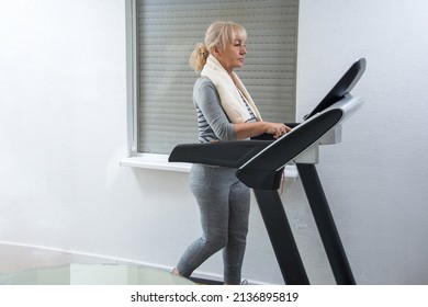 Sporty Mature Woman Walking On Treadmill At Home