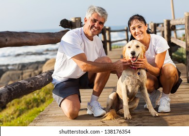 Sporty Middle Aged Couple And Pet Dog At The Beach In The Morning