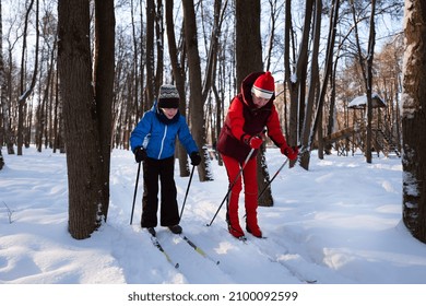 Sporty Mom Teaches Her Son To Ski In The Winter Park.
