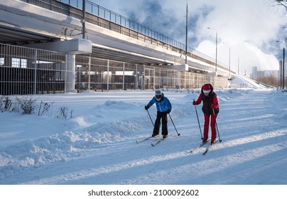 Sporty Mom Teaches Her Son To Ski In The Winter Park.
