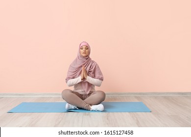 Sporty Muslim woman practicing yoga near color wall - Powered by Shutterstock