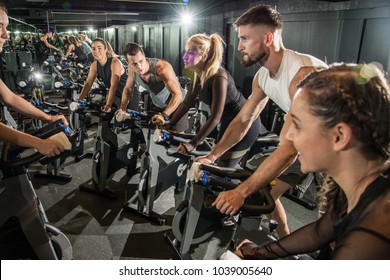 Sporty People Riding Exercise Bike Together On Cycling Class At Gym.