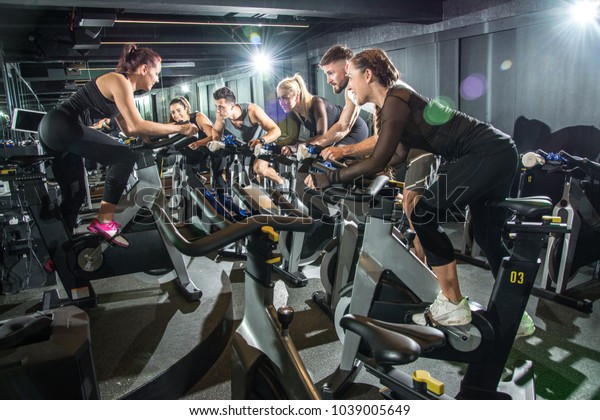 Sporty people riding indoor bicycles on cycling\
class in the gym.