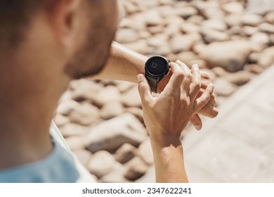 A sporty person using a smart fitness watch on his arm, running training, uses the app. Male trainer in fitness clothes. - Powered by Shutterstock