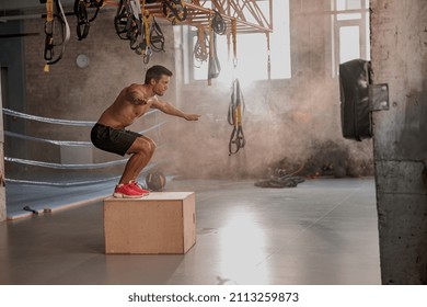 Sporty physically fit man doing step-up exercise on wooden box while doing gym training in sports club - Powered by Shutterstock