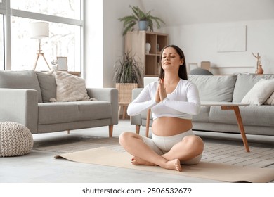 Sporty pregnant woman meditating on mat at home - Powered by Shutterstock