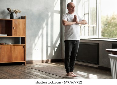 Sporty Senior Hispanic Man Working Out, Yoga In Basic Standing Asana Tadasana, Mountain Yoga Posture At Home.