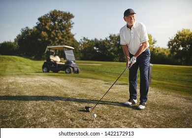 Sporty senior man about to make a shot with his driver while playing a round of golf on a sunny day - Powered by Shutterstock