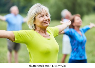 Sporty seniors stretch out their arms in a wellness yoga class in rehab - Powered by Shutterstock