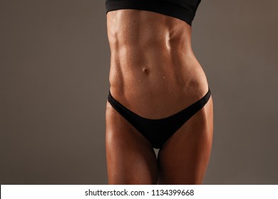 Sporty Sexy Girl With Great Abdominal Muscles In Black Sportswear On Black Background. The Pack Abs On Your Stomach Sweaty Wet Skin