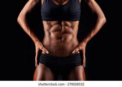 Sporty sexy girl with great abdominal muscles in black sportswear. Tanned young sexy athletic girl. A great sport female body close up.