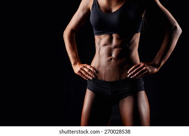 Sporty sexy girl with great abdominal muscles in black sportswear. Tanned young sexy athletic girl. A great sport female body close up.