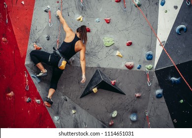 Sporty successful business woman being busy at her hobby-bouldering. Well equipped woman training in a colorful climbing gym, preparing to summer mountain ascend - Powered by Shutterstock