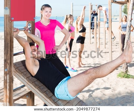 Sporty swiss positive women and men during training outdoors on sunny beach.
