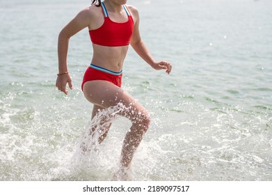 Sporty Teen Girl Running In Red Swimsuit In Sea