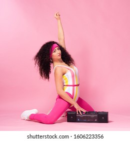 Sporty Woman In Aerobics Outfit With Retro Boombox. Studio Shot Of Wonderful Girl, Curly Hair. Pink Mock Up.