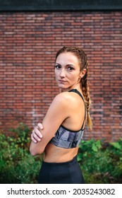 Sporty Woman With Boxer Braids Posing In Front Of A Brick Wall