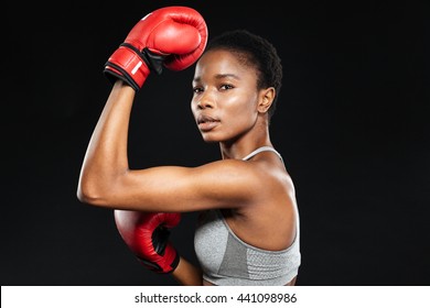 Sporty woman in boxing gloves looking at camera over gray background - Powered by Shutterstock