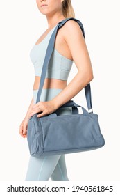 Sporty woman carrying blue duffle bag gym essentials studio shoot